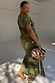 Khaki Shell Midi Dress with a gold seashell print and tie waist, shown on a model wearing size L.