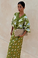 Khaki Eye Dorris Skirt with mystical eye and heart prints, styled with a matching cardigan and oversized beige clutch.