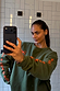 Khaki Sweatshirt with orange embroidered motifs on the sleeves and an oversized fit, shown in a casual selfie.