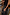 Thumbnail for Black Leather Fringe Bag with a plaited handle and long fringes, held by a model in a lifestyle setting.