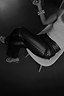 Thumbnail for Black vegan leather trousers with silver studs along the side, shown on a model sitting on a white chair.