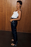 Thumbnail for Black Vegan Leather Studded Leg Trousers with silver side studs, styled with a white vest top and silver wedge sandals.