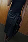 Black vegan leather wrap skirt with a tulip tie detail, styled with a black top and fringe bag.