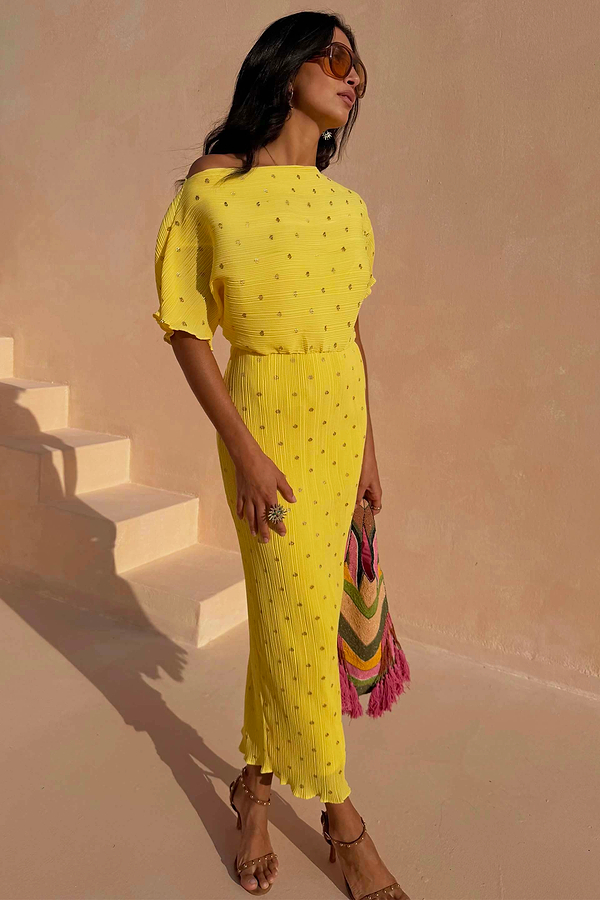 Sunshine Tilly Dress in yellow plissé with gold flecks and lettuce hem, styled with a colourful bag and sunglasses.