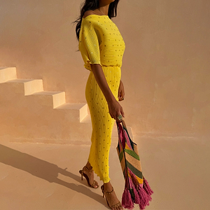 Yellow plissé Sunshine Tilly Dress with gold flecks, styled off-the-shoulder with a colourful tassel bag.