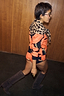 Iconic Leopard Knit Bandana tied around the shoulders as a multi-wear accessory over a vibrant orange knit set.