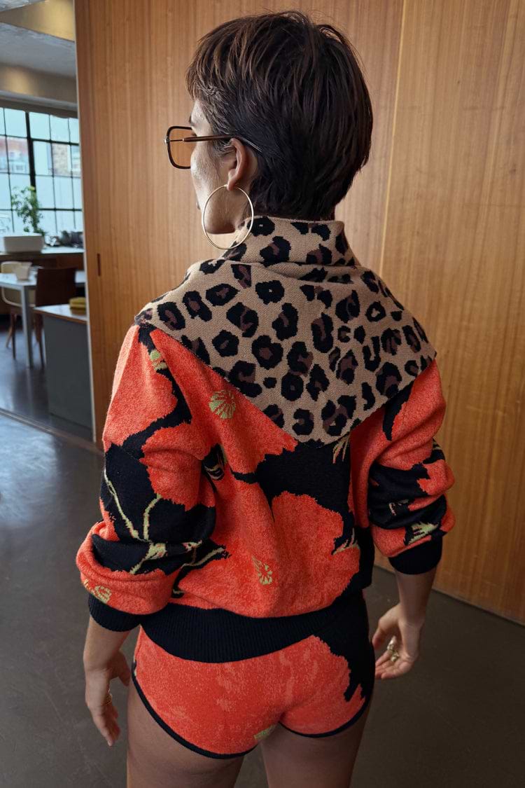 Iconic Leopard Knit Bandana in a soft-touch animal print, draped over the shoulders as a versatile layering piece.