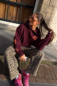 Iconic Leopard Barrel Jeans styled with a burgundy hoodie and pink trainers, sitting on street steps.