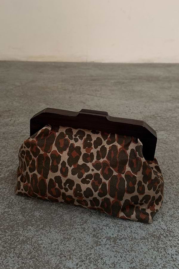Lucia Leopard Denim Bag with an iconic leopard print and dark wooden handle, shown on a textured grey floor.