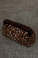 Lucia Leopard Denim Clutch Bag featuring an iconic animal print and a dark wooden handle on a textured ground.