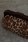 Lucia Leopard Denim Bag with a leopard print and dark wooden handle, resting on a textured surface.