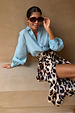 Iconic Brown Leopard Jaspre Skirt in sleek satin styled with a light blue shirt and sunglasses.