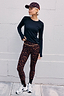 Dark Leopard Leggings featuring orange waistband detail, styled with a matching leopard cap and black long-sleeve top.