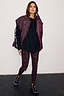 Dark Leopard Leggings in compressive fabric, styled with a black sweatshirt, matching puffer vest and black trainers.