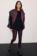 Dark Leopard Leggings in compressive fabric, styled with a black sweatshirt, matching puffer vest and black trainers.