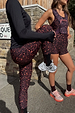 Dark Leopard Leggings in a burgundy animal print with orange accents, styled for activewear on a London street.