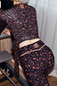 Thumbnail for Dark Leopard Leggings with orange contrast detailing and embroidered logo, worn with a wrap top on a Pilates reformer.