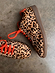 Leopard Pony Trainer featuring textured leopard print, vibrant orange laces, and a gum sole on a concrete surface.