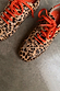 Leopard Pony Trainers with a leopard print leather upper and contrast orange laces on a grey stone floor.