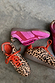 Leopard Pony Trainers with contrast orange laces and a pink panelled trainer shown from above on a grey floor.