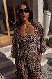 Leopard print bandeau swimsuit with blue whipstitch trim, matching balloon trousers and shirt in a vacation setting.