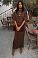 Lucia Leopard Tilly Dress in plisse leopard print with short sleeves, styled with a brown clutch at an outdoor cafe.