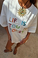 Relaxed white cotton T-shirt with colourful Life Is Tough Honey embroidered slogan.