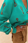 Turquoise Key Cardigan with a brown hand-painted key and lock print, styled with a gold bangle and brown skirt.