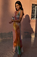 Abstract Malika Dress with a multicoloured print and draped neckline, styled on a model against a textured pink wall.