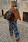Tan brown Cowgirl Martha Cardigan with an embroidered western motif, draped over a paisley co-ord on a cobbled street.