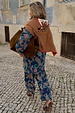 Tan brown Cowgirl Martha Cardigan with an embroidered western motif, draped over a paisley co-ord on a cobbled street.