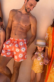 Men's Orange Sun Swim Shorts with a recycled Soleil print and drawstring waist, styled as a matching family look.