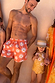 Men's Orange Sun Swim Shorts with a recycled Soleil print and drawstring waist, styled as a matching family look.