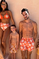 Men's Orange Sun Swim Shorts featuring the Soleil print and drawstring waist, styled as matching family swimwear.