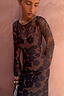 Tan Jaden Floral Mesh Dress with sheer flared sleeves and a high neckline on a model against a textured wall.