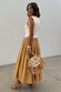 Camel Monika Dress with a cream corset-style top and pleated camel midaxi skirt, styled with a straw bag.