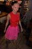 Thumbnail for Red and Pink Mini Monika Dress with a panelled corset top and pleated skirt, shown in a motion-blurred evening style.