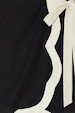 Mono Scallop Mini Jaspre Skirt detail showing the black linen-blend fabric with a cream scallop trim and wrap tie.