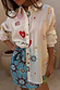 Sheer cream Morocco Charms Marley Shirt with heart and sun motifs, styled with a vibrant blue printed wrap skirt.