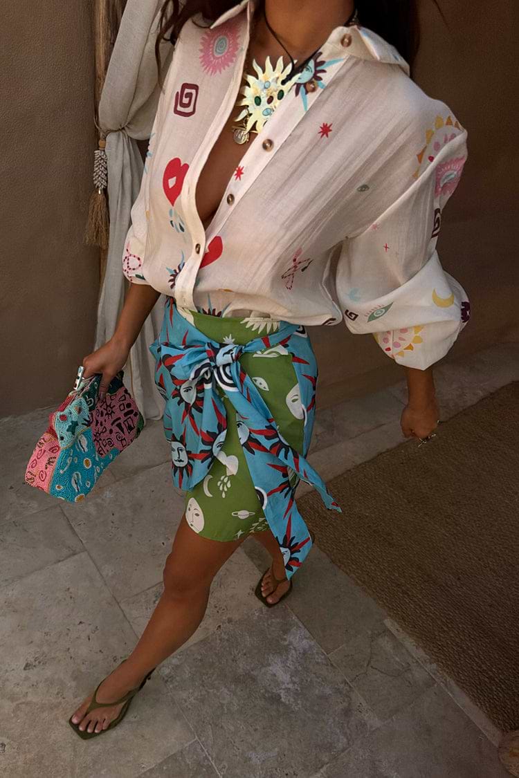 Cream Morocco Charms Marley Shirt featuring sheer fabric and sun motifs, styled with a green mini skirt.