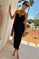Multi Spot Megan Dress in black plisse with multicoloured flecks and cross-front straps, styled for a summer vacation.
