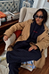 Navy Book The Flight Jumper with red text, layered with a tan studded trench and pinstripe trousers.