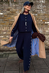 Navy Studded Knit Jogger co-ord with silver side studs, styled with a camel trench coat, navy cap and sunglasses.