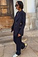 Navy Pinstripe Arden Trousers and matching blazer with sun and eye embroidery, styled with silver trainers.