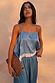 Deloris Thin Chain I Love You Necklace in brass with a spinning pendant, styled with a blue lace-trim top and spotted clutch.