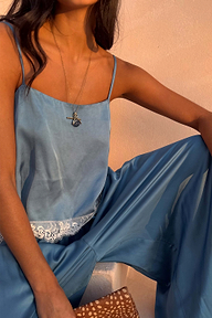 Deloris Thin Chain I Love You Necklace in brass with a spinning pendant and lariat drop, worn with a blue set.