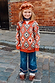 NFD Kids Diamond Bomber in a rust orange knit with a bold diamond pattern, worn by a child on a London street.