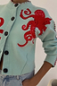 Thumbnail for Blue Octopus Cardigan featuring red embroidered octopus motifs and contrast blanket stitch detailing.