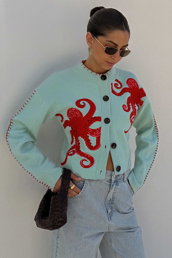 Blue Octopus Cardigan with red embroidered motifs and blanket stitch detail, styled with light wash jeans.