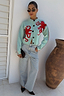 Soft blue knit Octopus Cardigan featuring red embroidered motifs and blanket stitch, styled with light-wash jeans.